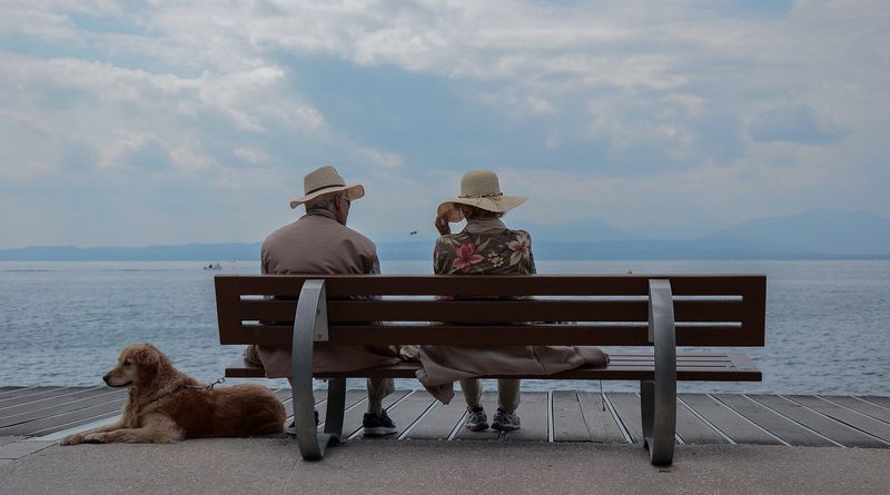 pareja de ancianos sentados en un banco mirando al mar